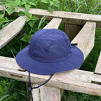 Indigo blue acrylic bucket hat in a three-quarter view, with a fine grid texture, stitched brim and chin toggle.