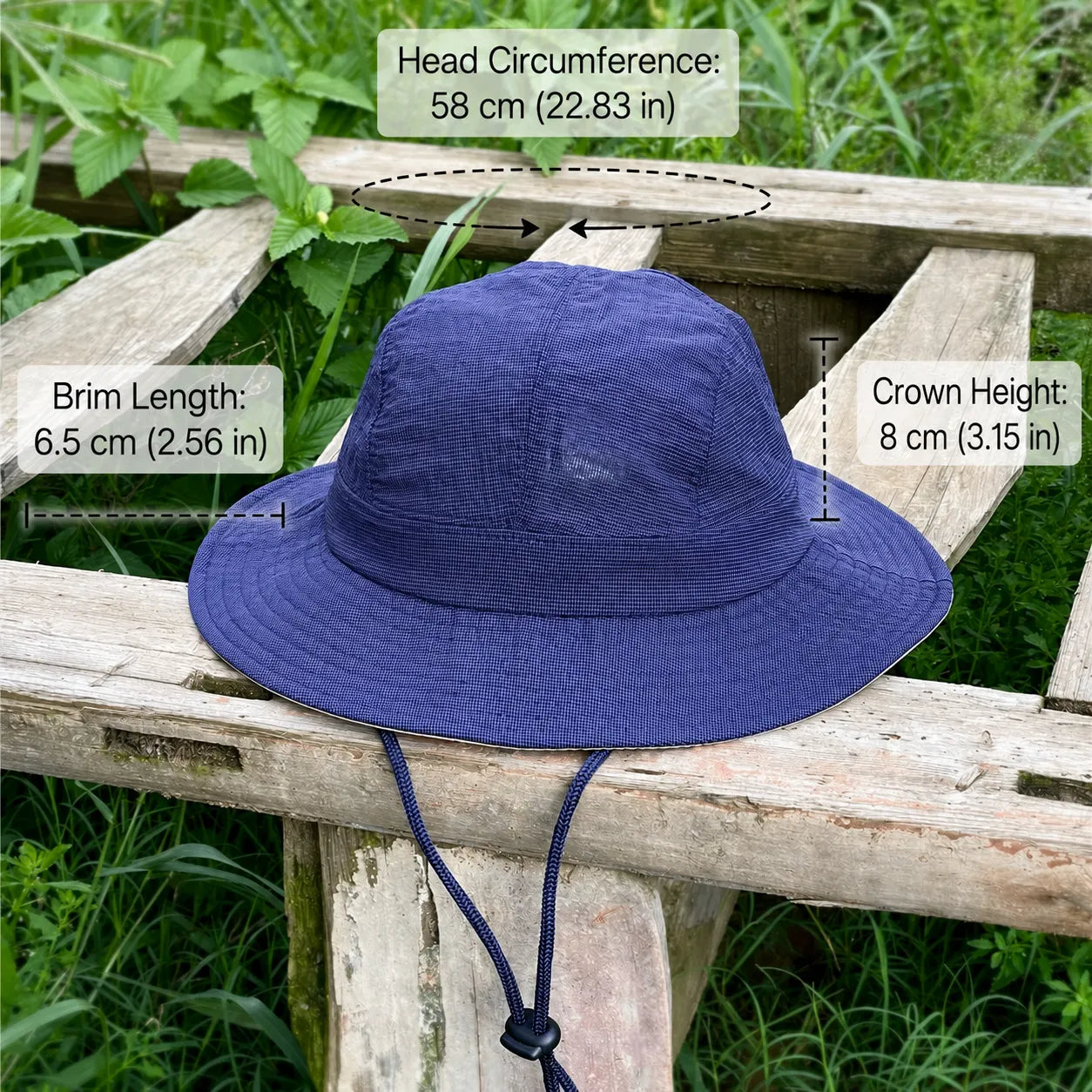 Indigo blue acrylic sun hat with a 58 cm fit, 6.5 cm brim and 8 cm crown, pictured outdoors with a chin toggle.