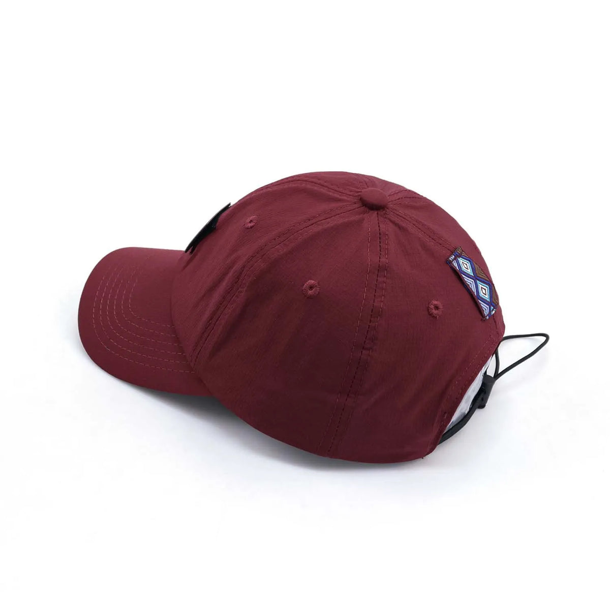 Adjustable baseball cap in burgundy, rear view with an elastic drawcord, geometric side patch and panel stitching