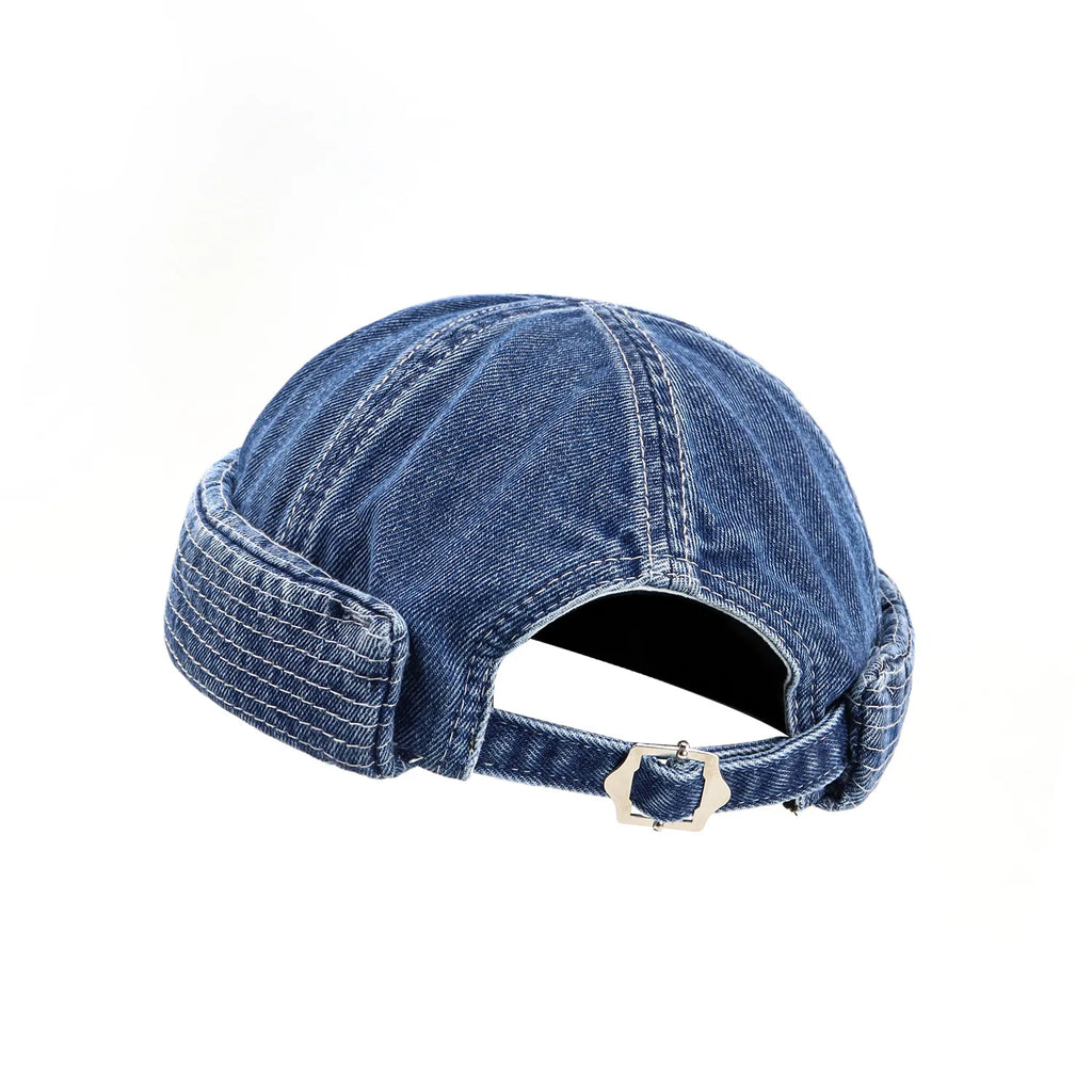 Adjustable docker cap in washed indigo, rear detail with an arched opening, denim strap and polished metal buckle
