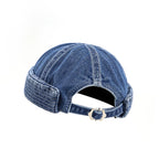 Adjustable docker cap in washed indigo, rear detail with an arched opening, denim strap and polished metal buckle
