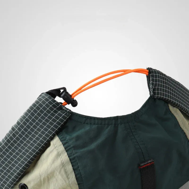 Adjustable docker cap detail in forest green and beige, showing the orange elastic drawcord, toggle and checked cuff