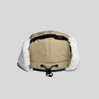 Adjustable ear flap cap in khaki, rear view with a black crown strap, toggle drawcord and white faux-fur panels
