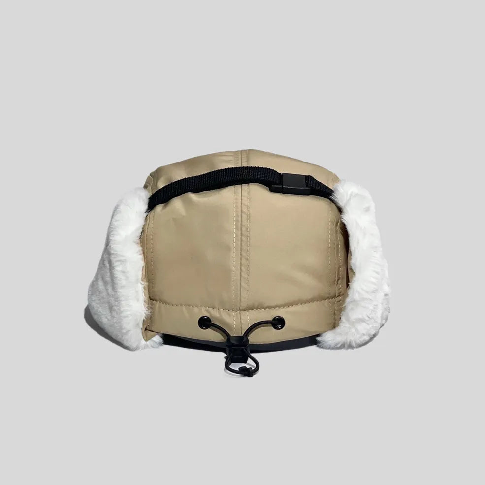 Adjustable ear flap cap in khaki, rear view with a black crown strap, toggle drawcord and white faux-fur panels
