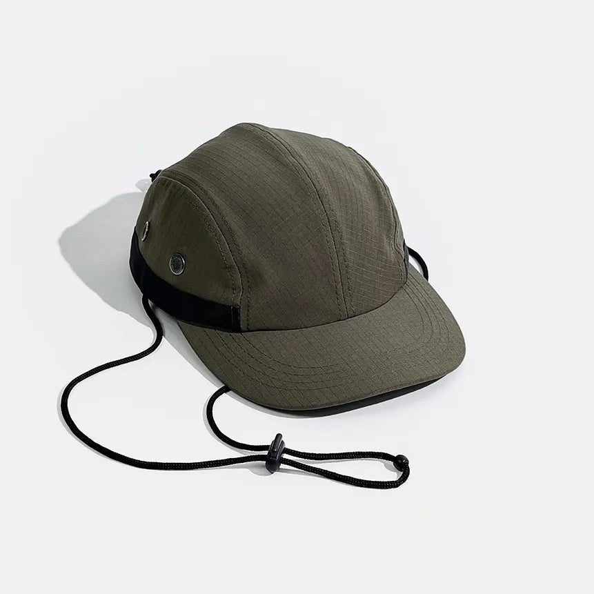Adjustable hiking cap in olive green, angled front view with a grid-textured crown, metal eyelets and toggle cord