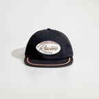Front view of a black baseball cap with an oval racing patch, tan rope trim and a flat brim for casual streetwear.