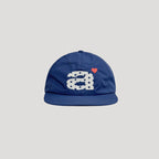 Blue nylon cap front view with oversized graphic embroidery and small heart detail
