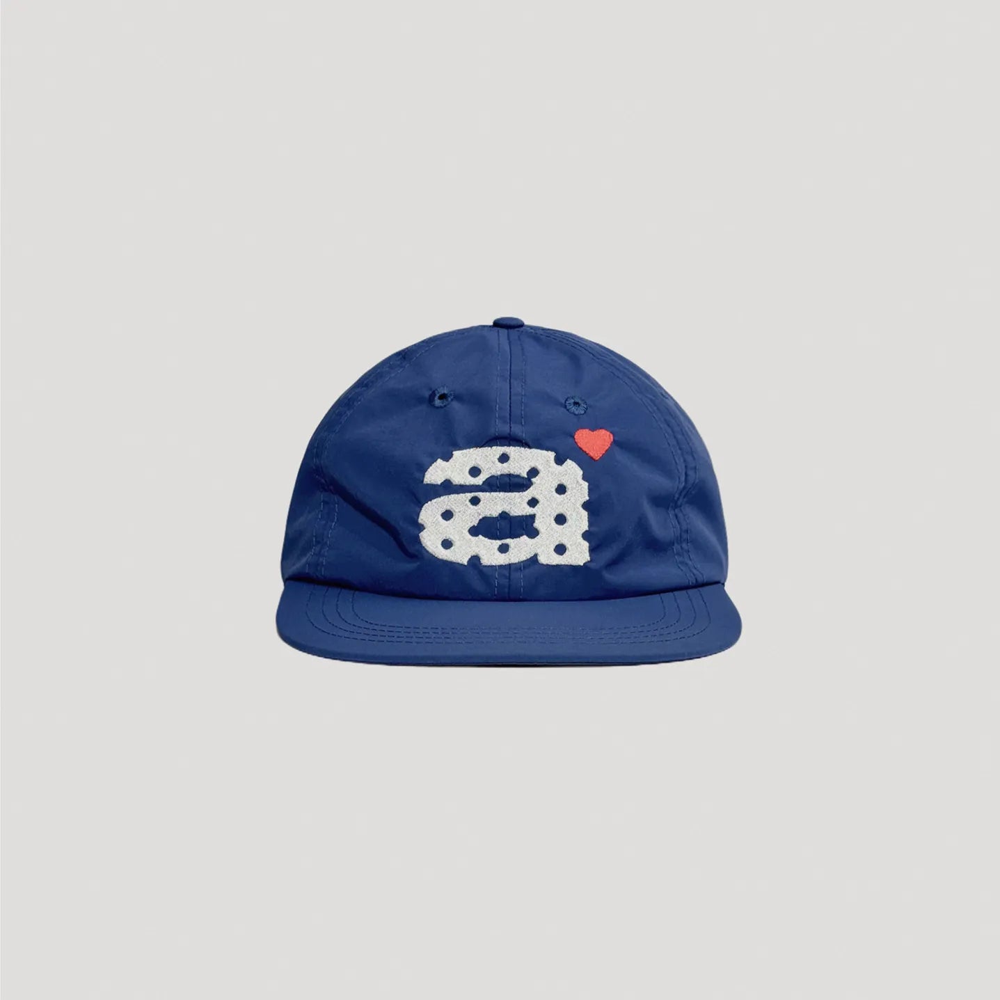 Blue nylon cap front view with oversized graphic embroidery and small heart detail
