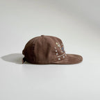 Side profile of a brown cotton baseball cap with a flat brim and structured crown for casual styling