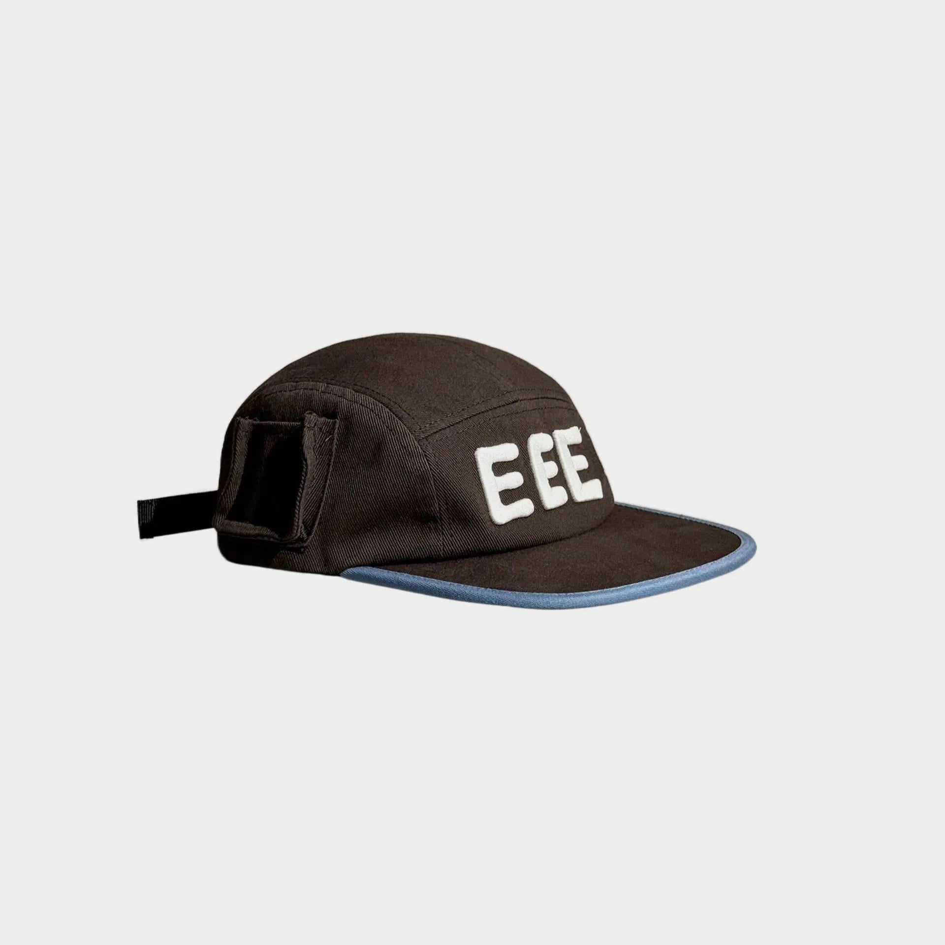 Side view of a brown five-panel cap with raised white EEE embroidery, a flat brim with light blue trim and a black bow detail.