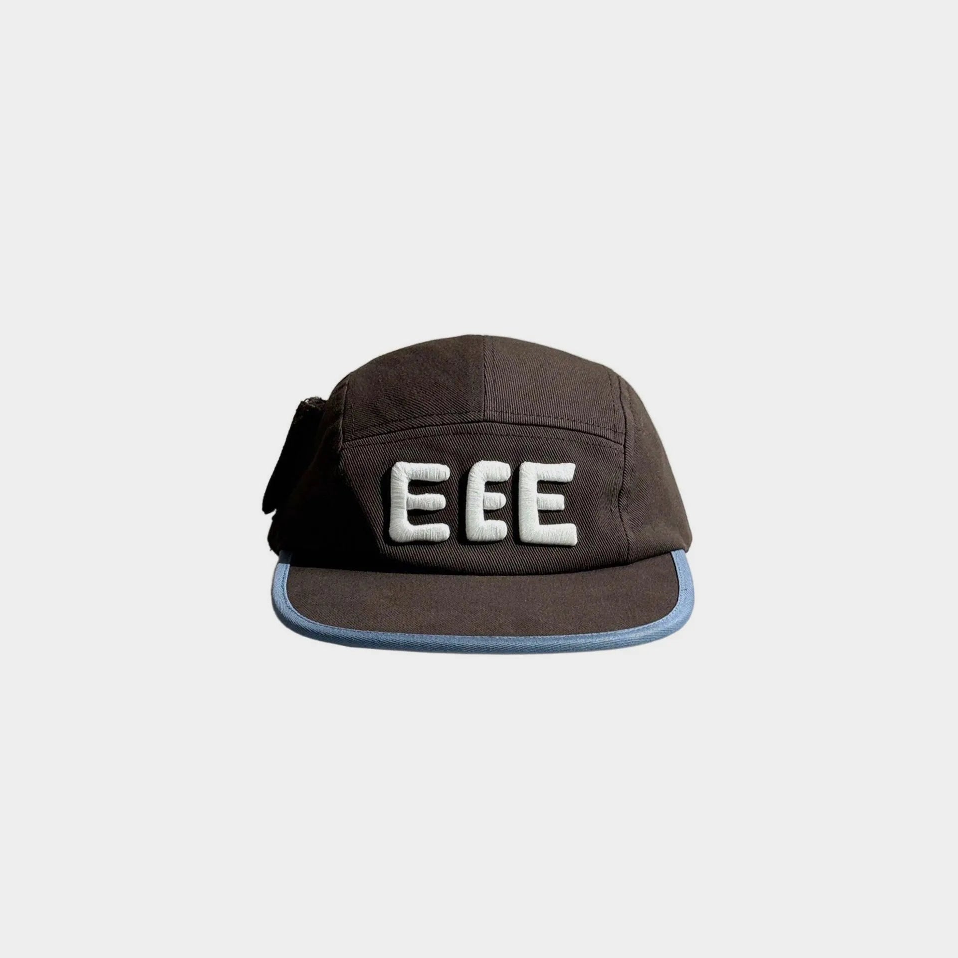 Front view of a brown five-panel cap with raised white EEE embroidery, light blue brim trim and a black side bow detail.