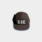 Front view of a brown five-panel cap with raised white EEE embroidery, light blue brim trim and a black side bow detail.
