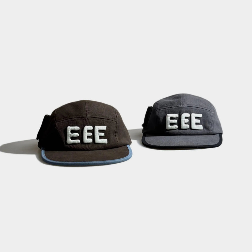 Top view of brown and grey five-panel caps with raised white EEE embroidery, flat brims and contrast edge trim.