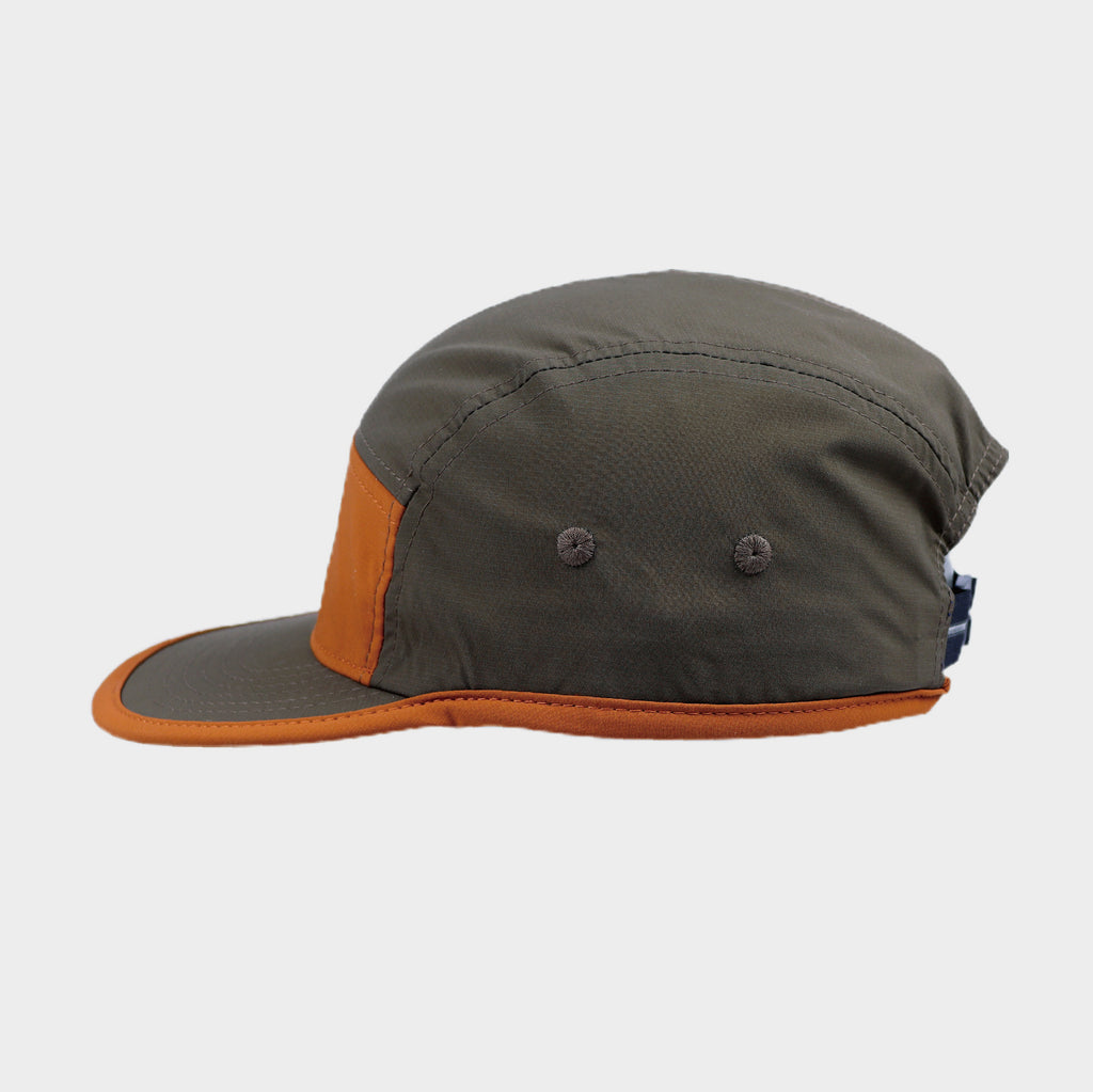 Side view of a brown and orange five-panel cap featuring contrast trim, panel stitching and two embroidered ventilation eyelets.