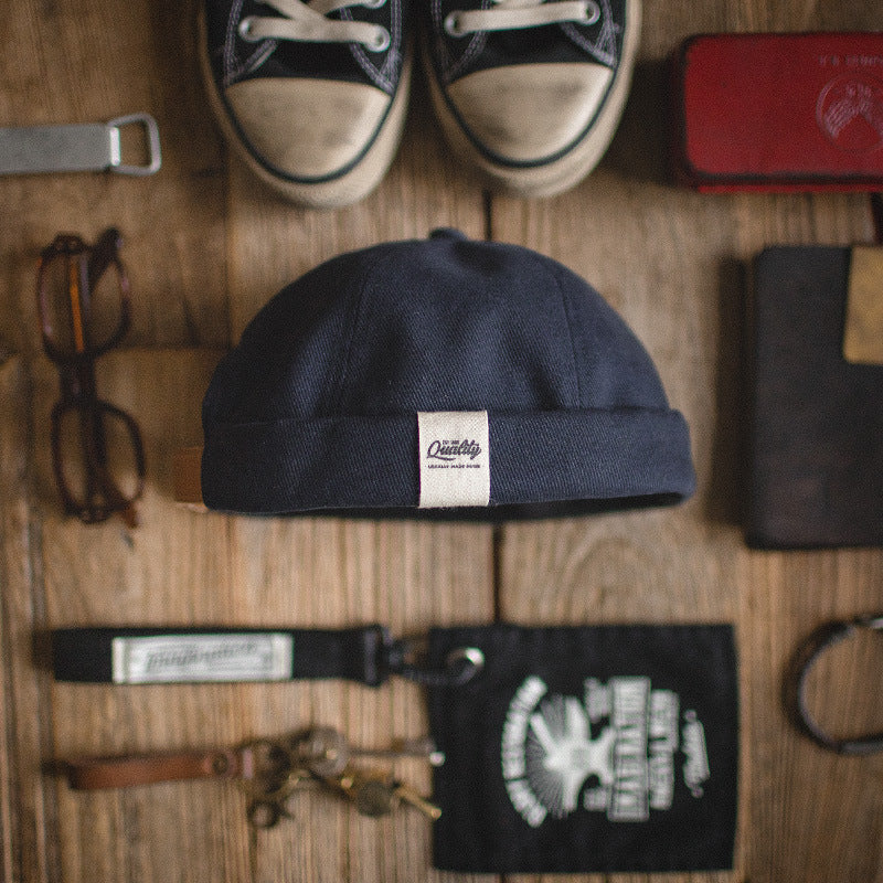Navy cotton docker cap with a clean rolled-cuff design styled alongside everyday casual accessories