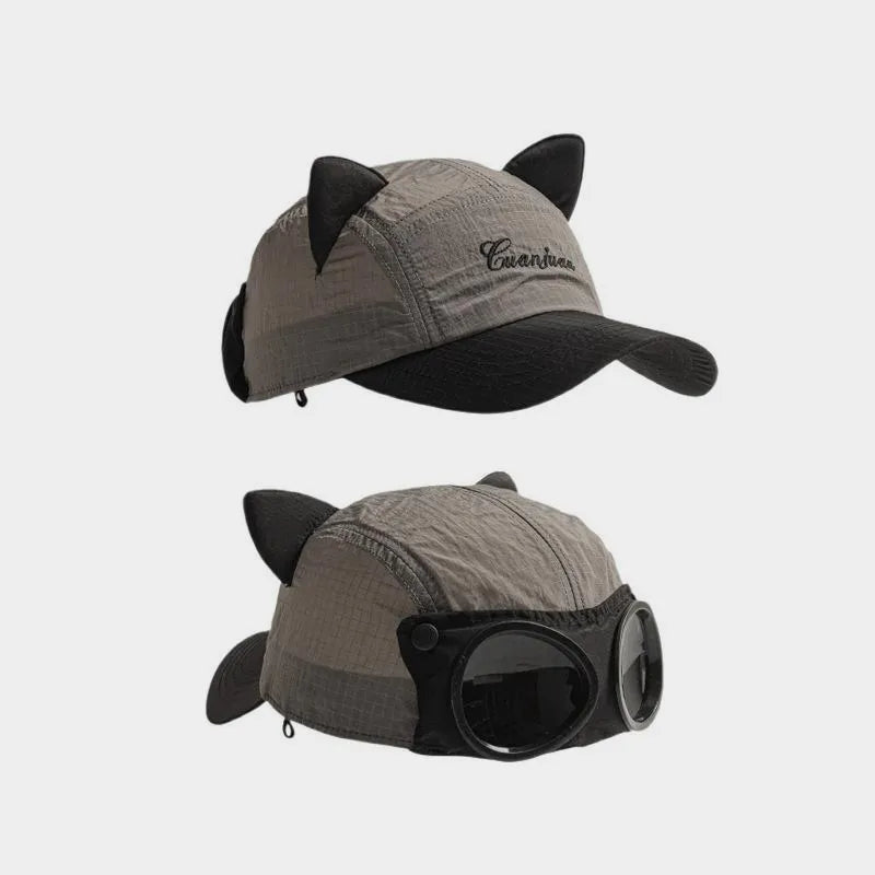 Grey cat ear baseball cap with black accents, shown from the curved brim and decorative goggle sides.