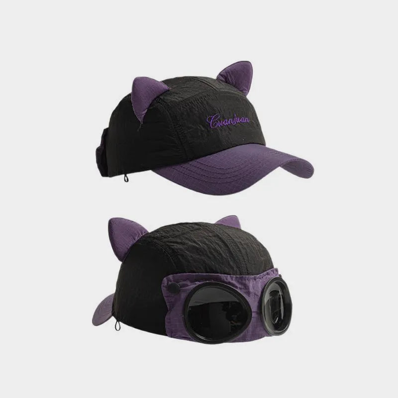 Black cat ear cap with purple brim and ears, shown from the embroidered front and decorative goggle back.