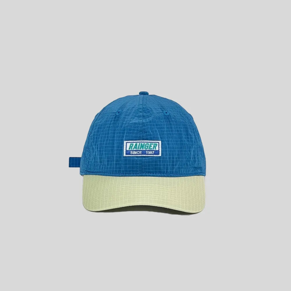Colour block baseball cap in blue and pale yellow, front view with a woven slogan badge and curved stitched brim
