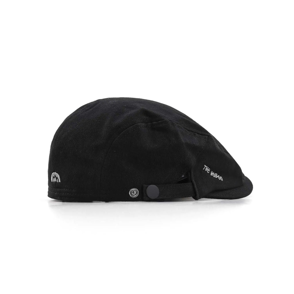 Cotton flat cap in black, side view with a short peak, embroidered lettering and snap-tab adjustment