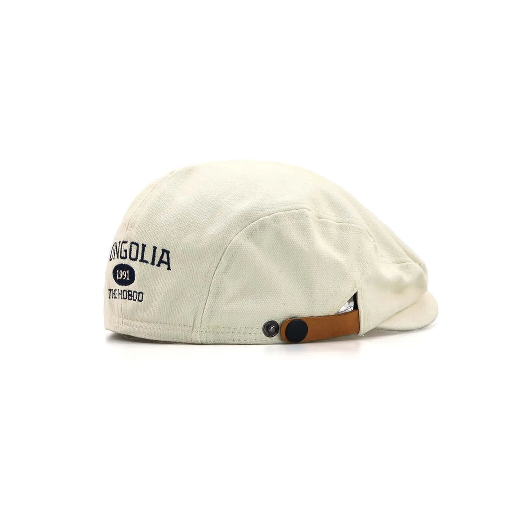 Embroidered cotton ivy cap in cream, angled from the rear with MONGOLIA 1991 lettering and a tan press-stud tab