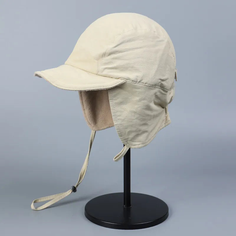 Cream fleece lined ear flap cap in a front side view with a short peak and warm ear panels.