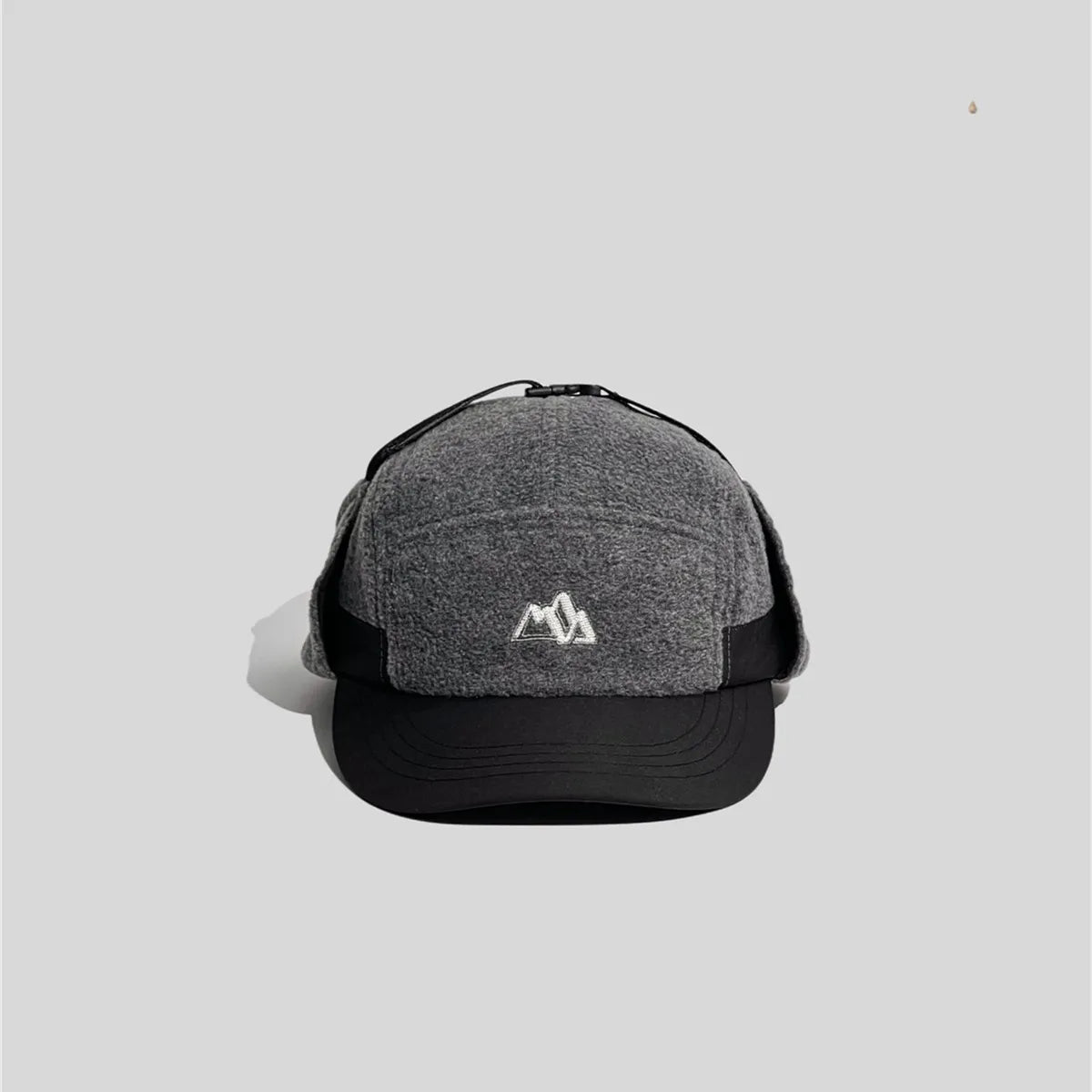 Fleece ear flap cap in heather grey and black, front view with a curved peak and mountain embroidery