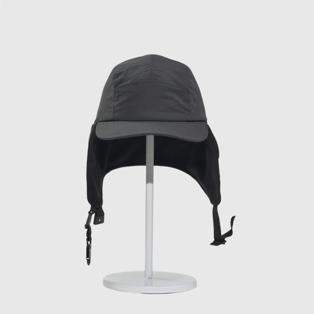 Black fleece-lined winter cap front view with ear flaps down, curved peak and hanging buckle straps.