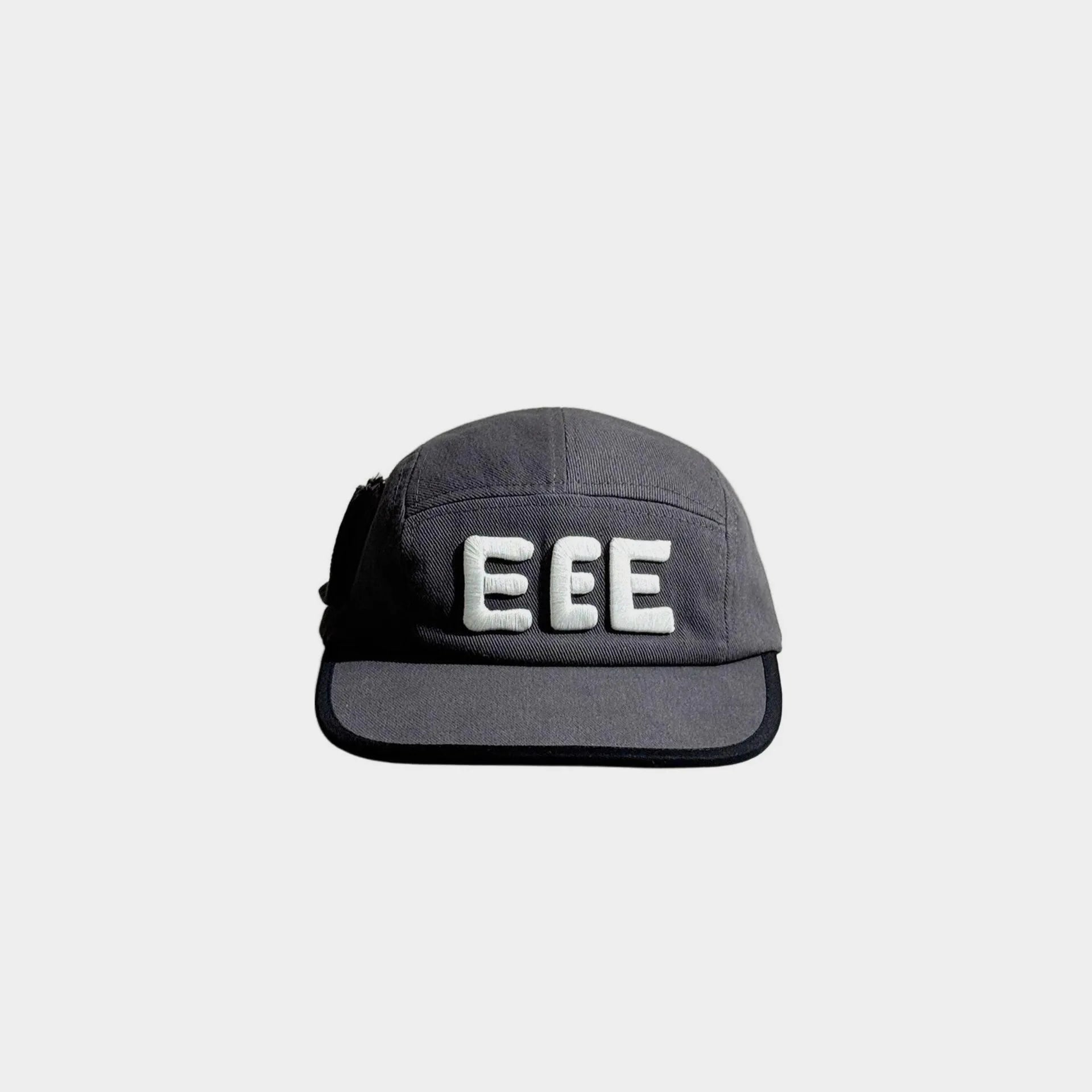 Front view of a grey five-panel cap with raised white EEE embroidery, black brim trim and a black side bow detail.