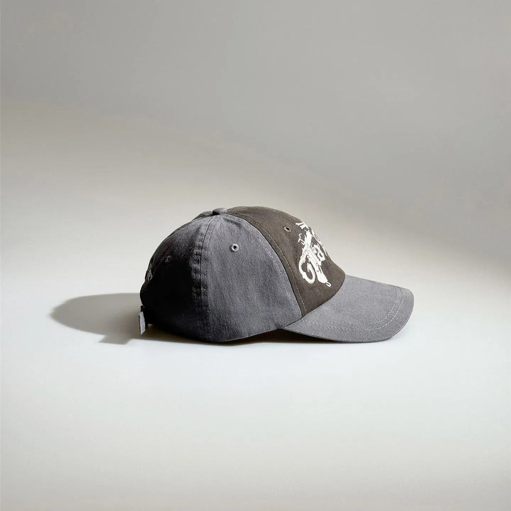 Side view of a grey two-tone baseball cap with gothic embroidery, contrast panels and an adjustable back strap.
