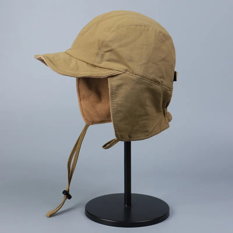 Khaki ear flap cap in side profile with soft lining, extended ear flaps and a neat short brim.