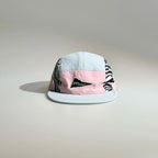 Front view of a light blue and pink color-block five-panel cap with zebra print side panels, a triangle logo patch and flat brim.