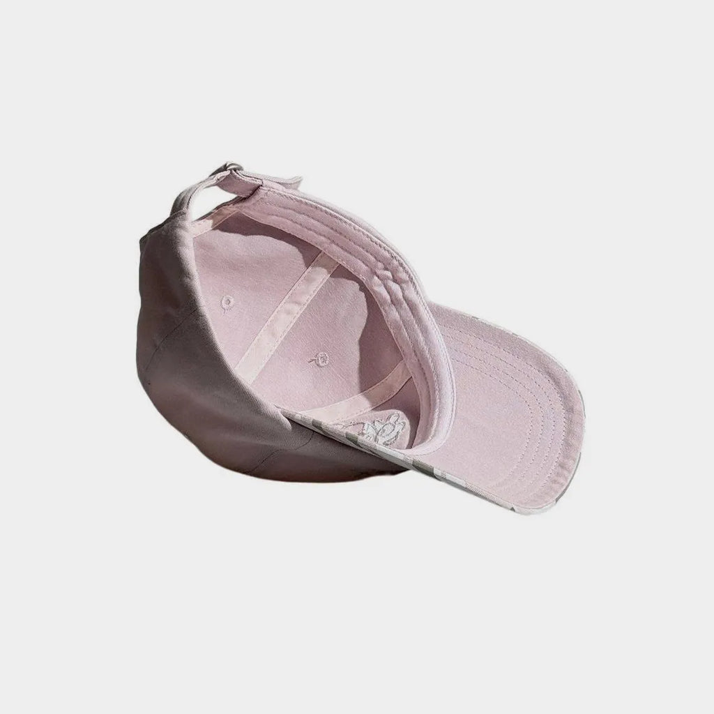 Interior view of a light pink baseball cap showing the inner panel construction, stitched curved brim and adjustable back strap.