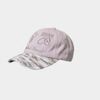 Side view of a light pink baseball cap with bear, HUG and bone embroidery and a pink camouflage curved brim.