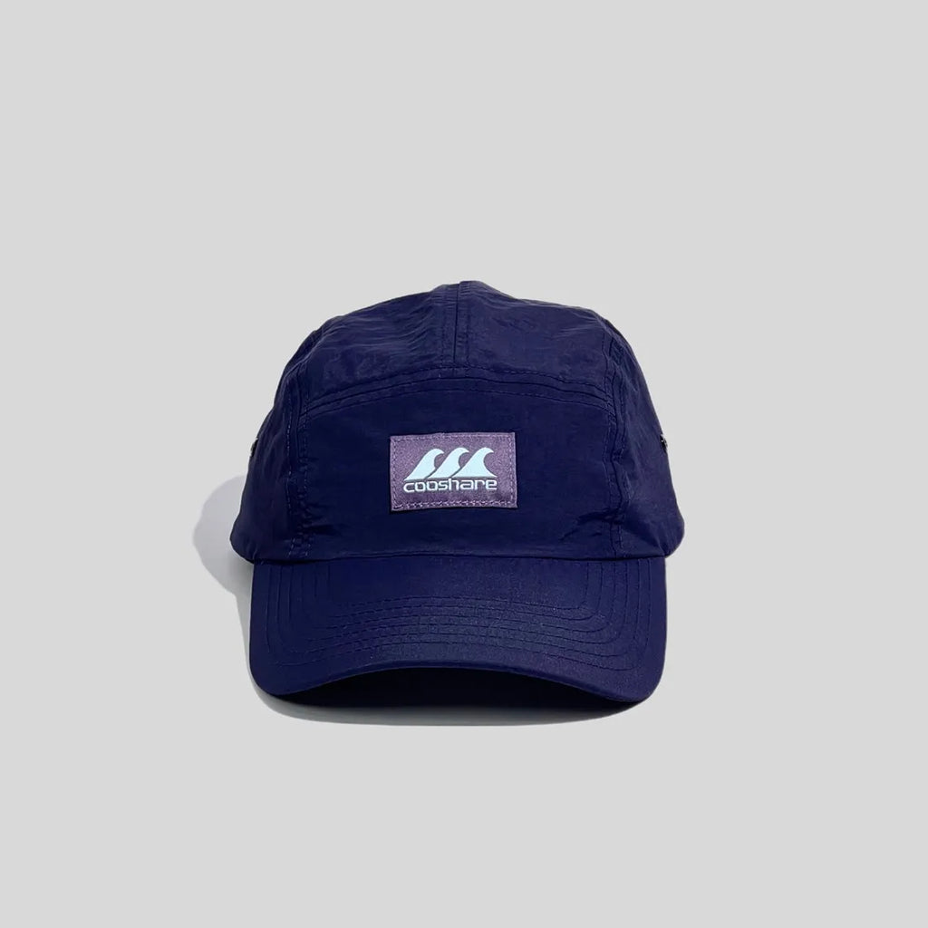 Logo-patch sports cap in navy blue, front view showing the central woven badge, low crown and curved stitched peak