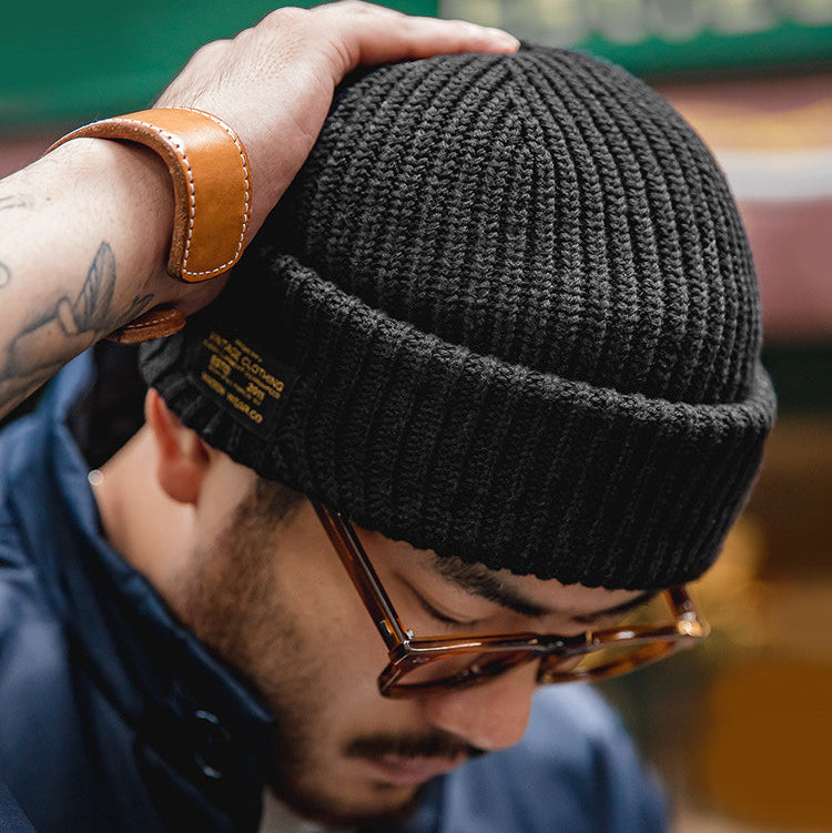 Man styling a black cotton cuffed beanie with glasses and a casual streetwear jacket