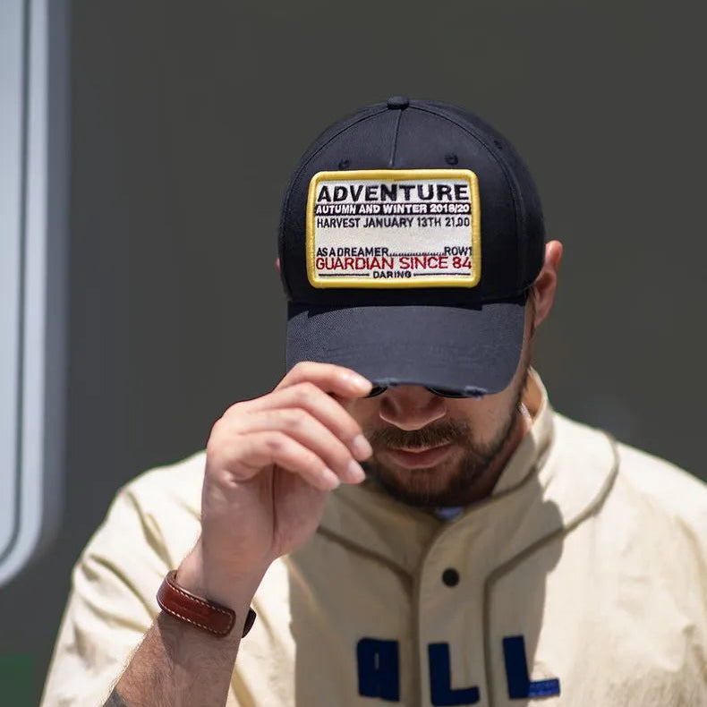 Man wearing a navy cotton baseball cap with an Adventure embroidered patch