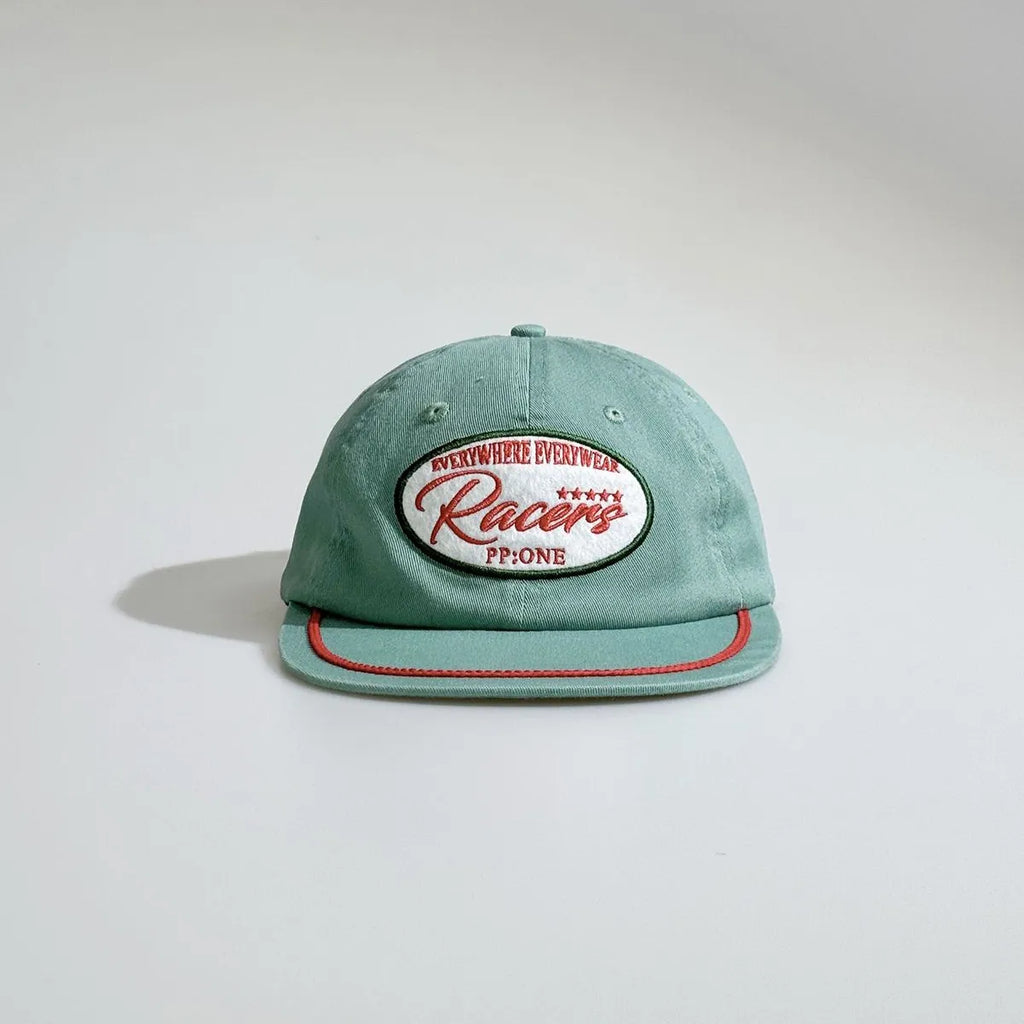 Front view of a mint green baseball cap featuring an oval racing patch, embroidered eyelets and red rope detail across the brim.