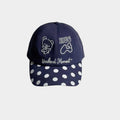 Front view of a navy baseball cap with white bear, HUG and bone embroidery, script lettering and a white polka dot curved brim.