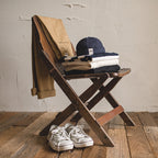 Navy cotton brimless cap styled with folded knitwear, casual trousers and canvas shoes for a vintage everyday look