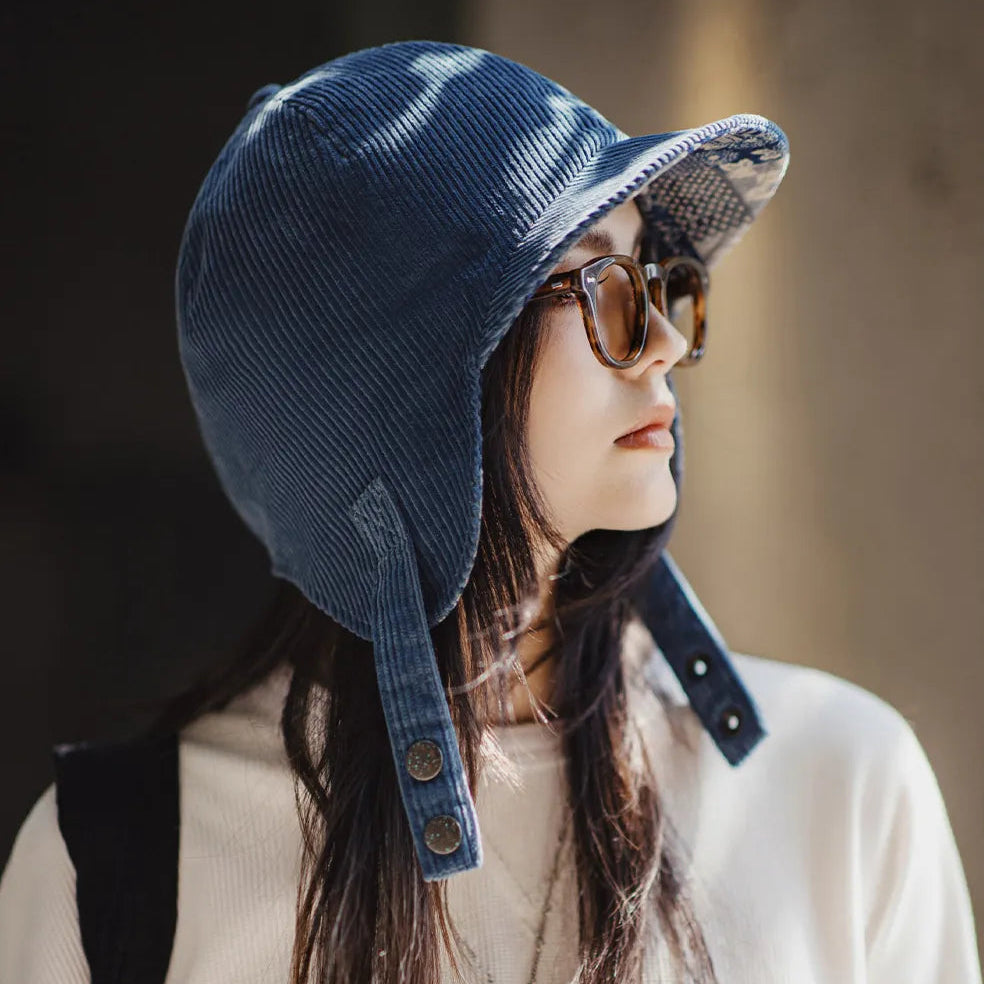 Side view of a woman wearing a navy corduroy trapper-style cap with extended ear coverage