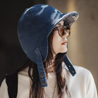 Side view of a woman wearing a navy corduroy trapper-style cap with extended ear coverage