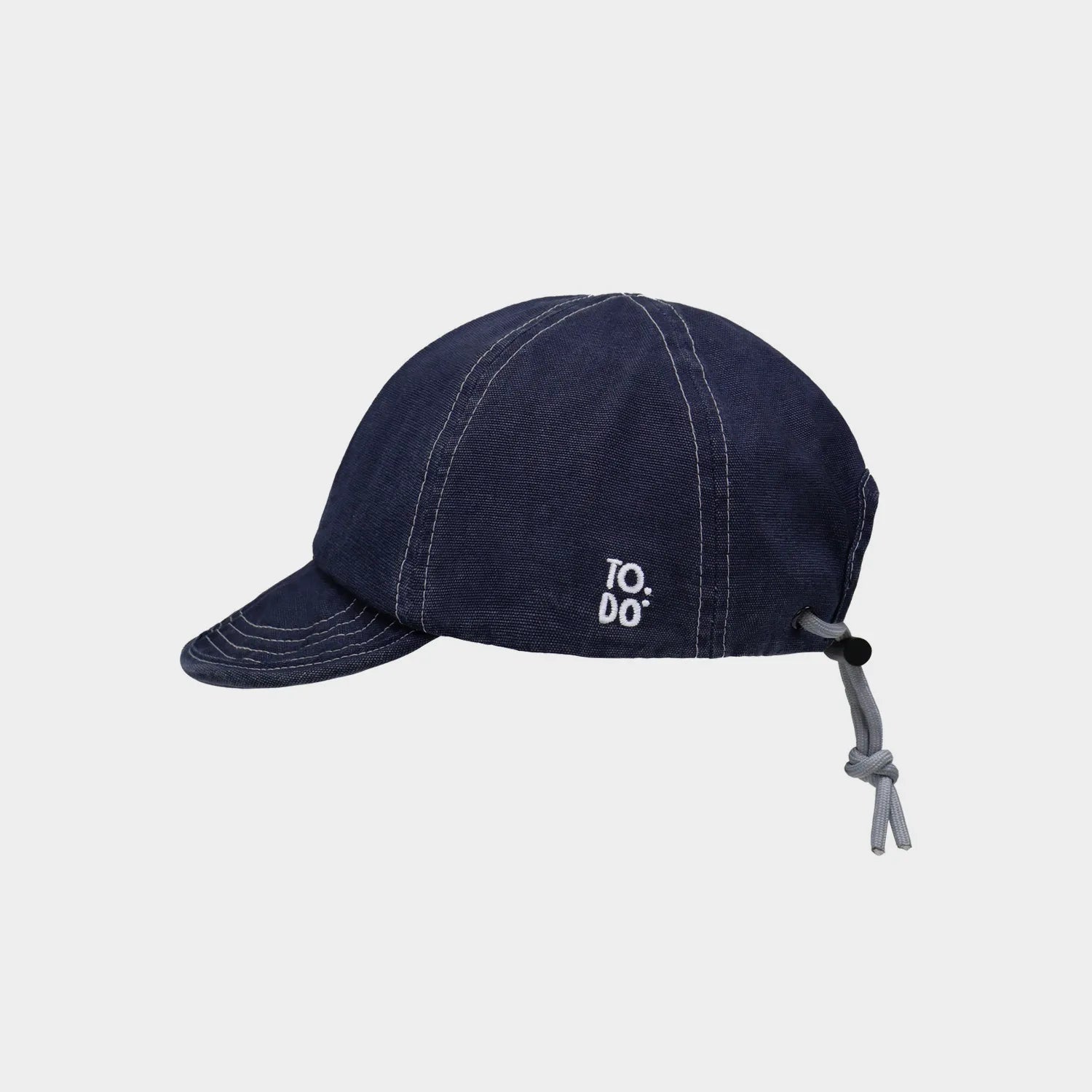 Side view of a navy cotton short brim cap with small white embroidery and rear drawcord adjustment