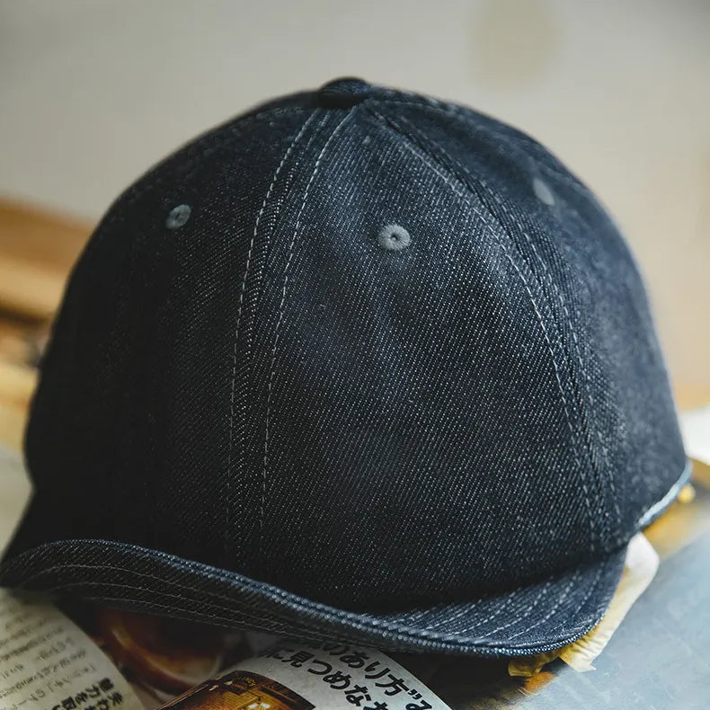 Indigo six-panel denim baseball cap with tonal eyelets, curved brim and visible twill texture