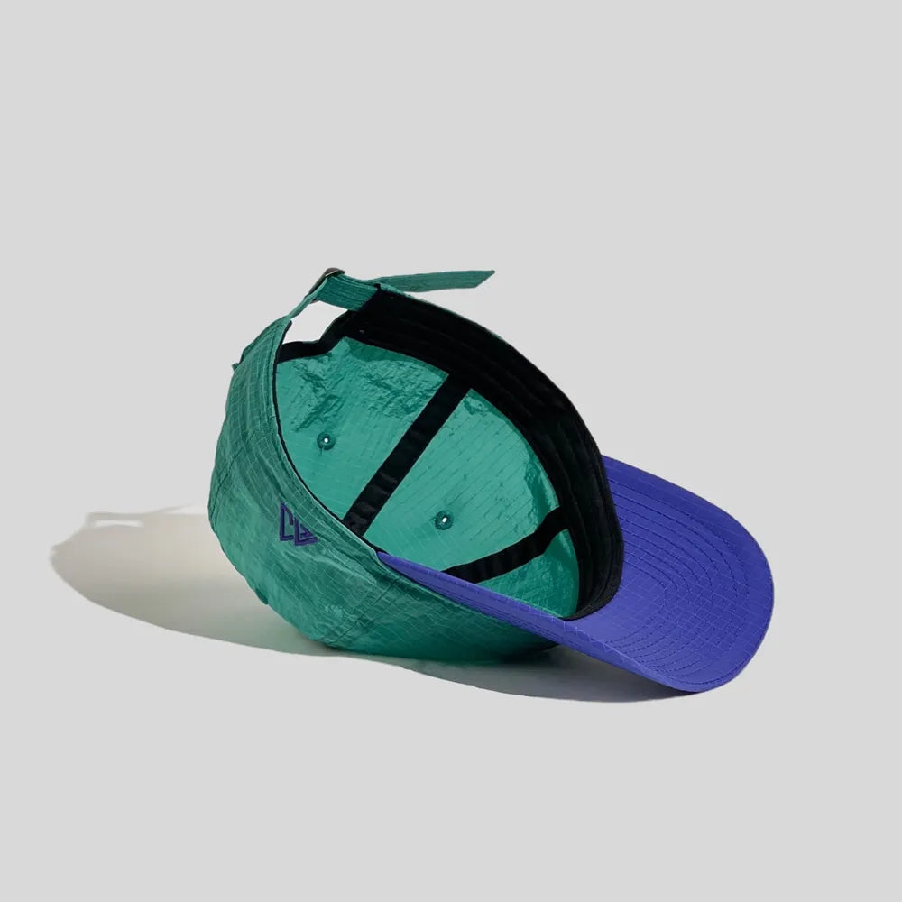 Nylon baseball cap in teal green and purple, interior view showing the black sweatband and taped crown seams