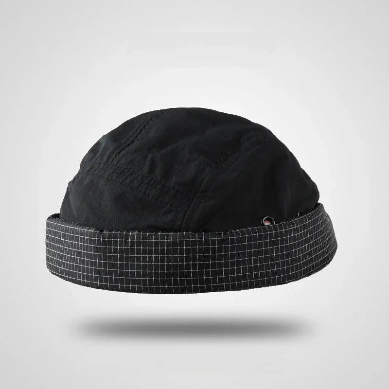 Nylon docker cap in black and charcoal grey with a checked cuff, metal eyelets and a brimless shape
