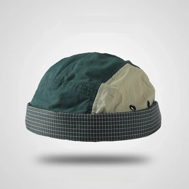 Nylon docker cap in forest green, beige and charcoal grey with a checked cuff, metal eyelets and a brimless shape