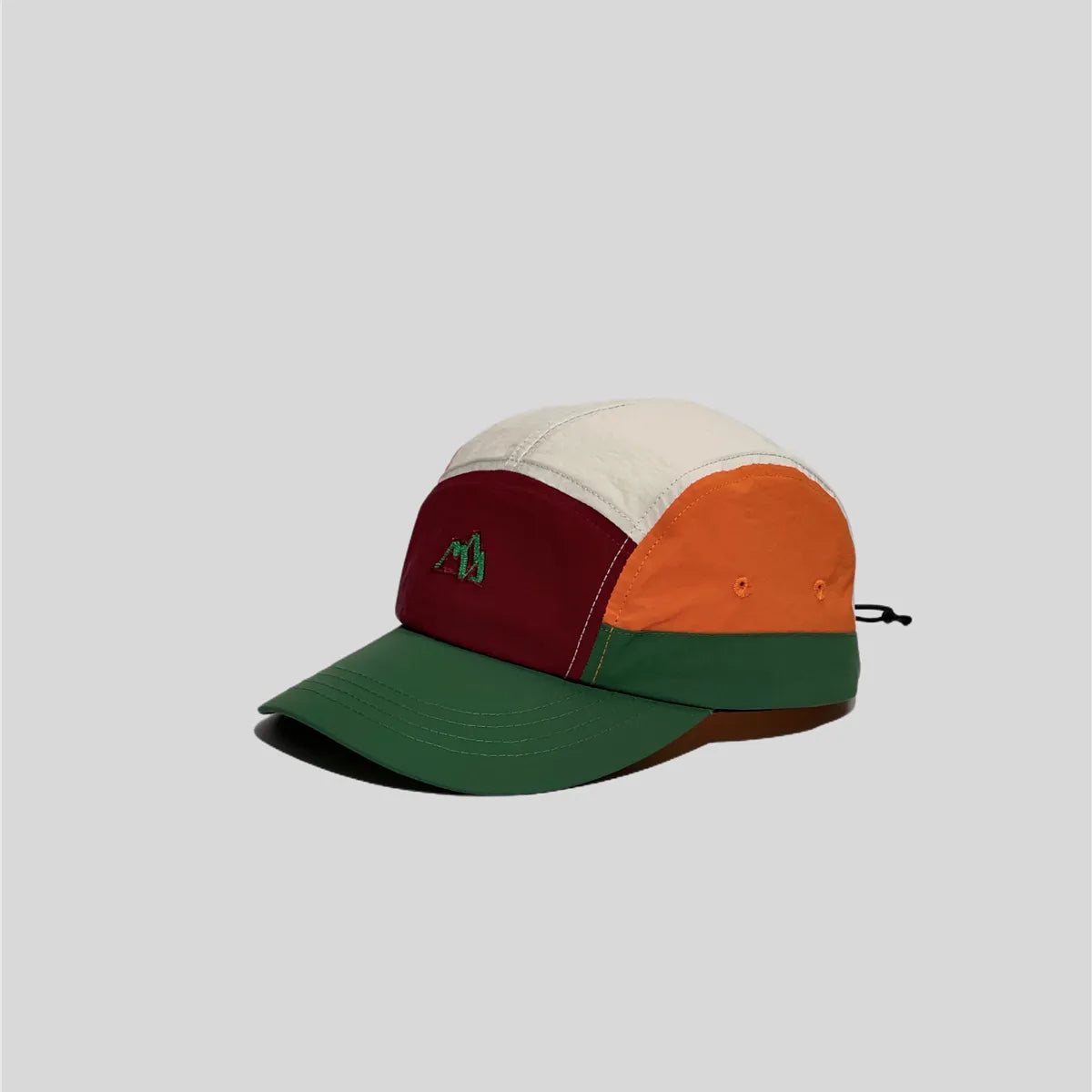 Nylon five panel cap in cream, burgundy, orange and green, angled view with curved brim, eyelets and mountain embroidery