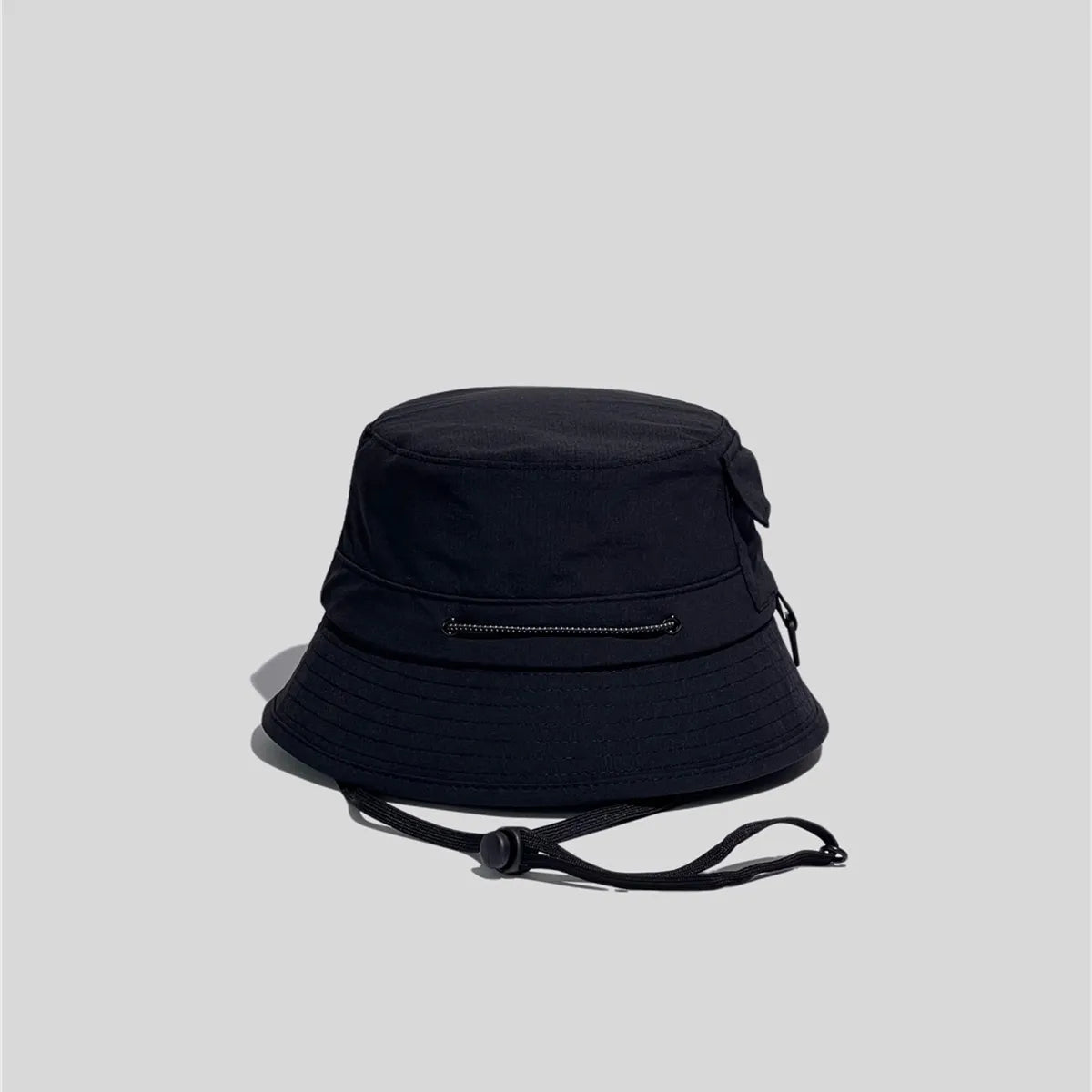 Nylon outdoor bucket hat in black, cord-side view showing the adjustable crown cord and multi-row brim stitching