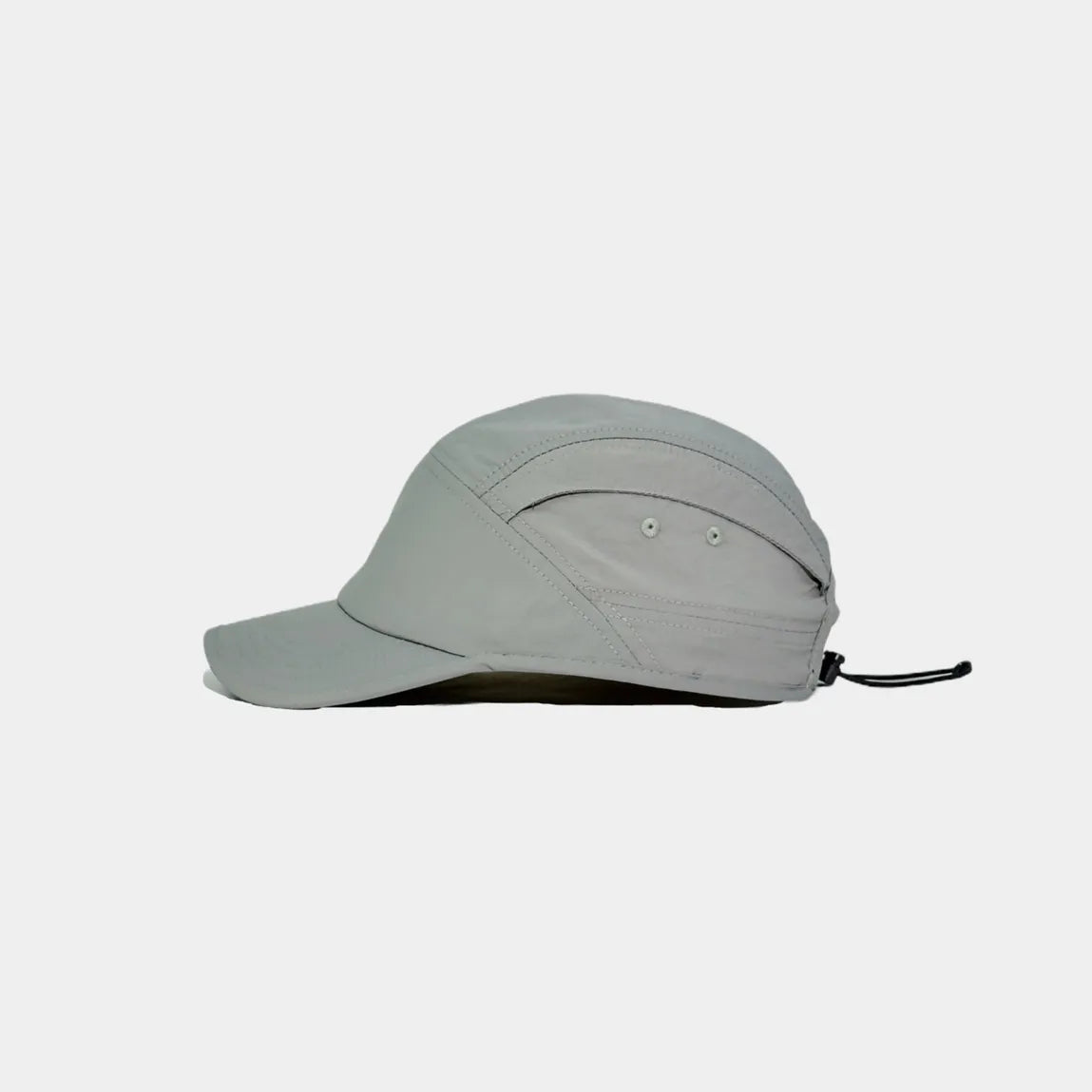 Nylon outdoor cap in light grey, side view showing two eyelets, curved seams and rear drawcord adjuster