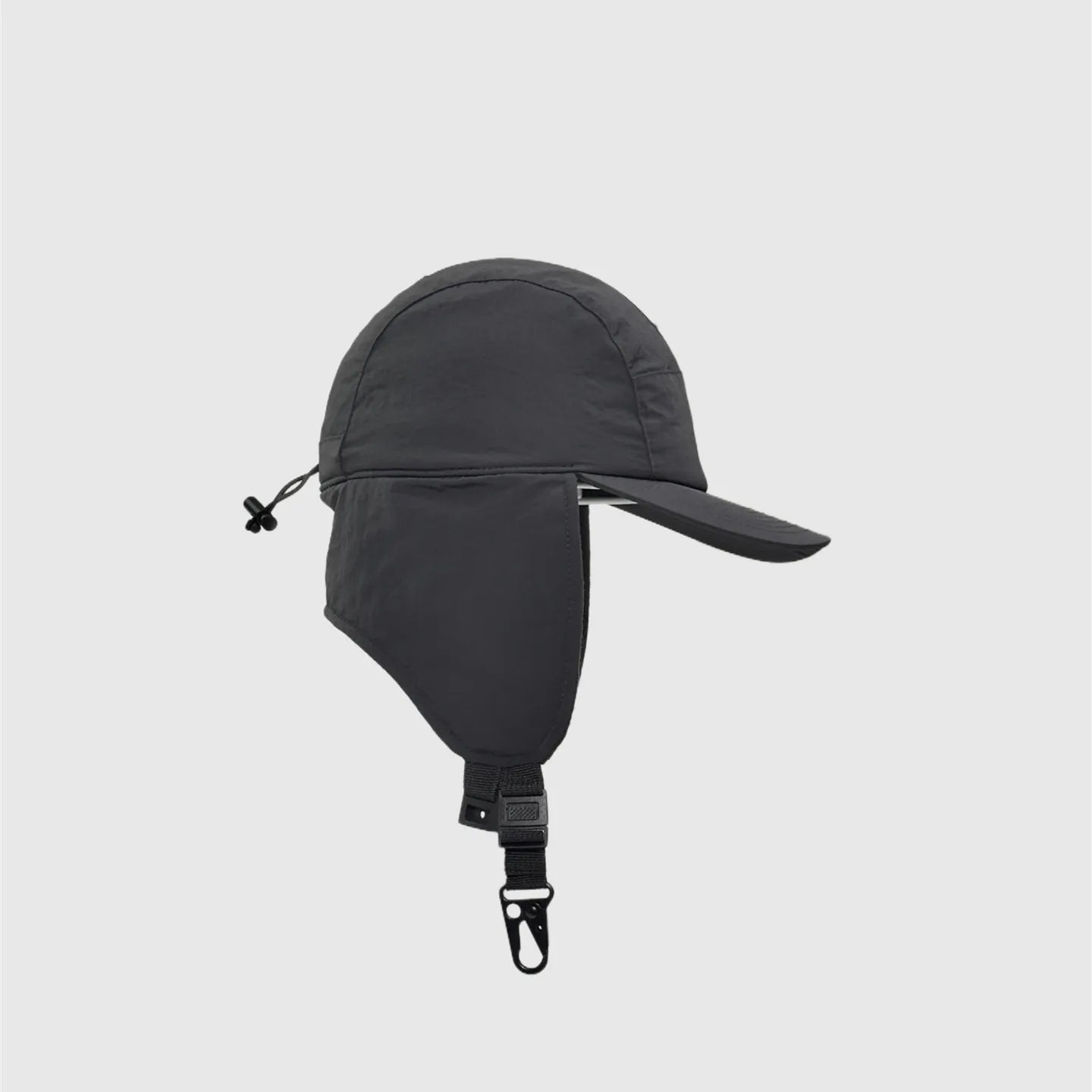 Dark grey nylon winter baseball cap side view with long ear flap, curved peak and rear drawcord.